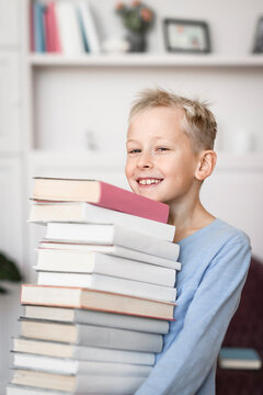 Portrait of smiling blond boy carrying stack of books