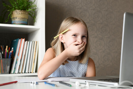 Laughing girl sitting at table at home using laptop