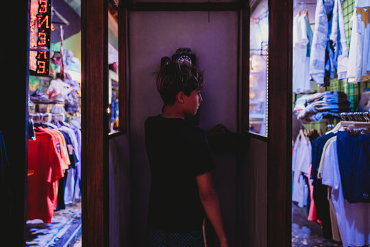 Boy inside a phone booth inside a clothing store.