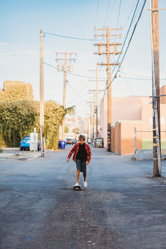 Boy riding his skateboard on an alley way.