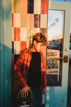 Boy looking down while holding his skateboard