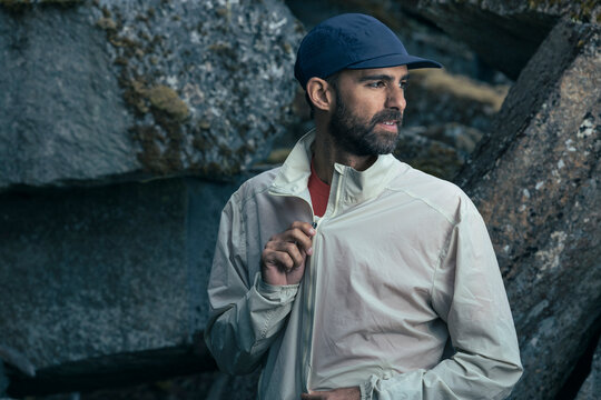 Trail runner on rocky landscape puts on technical windbreaker