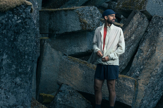 Trail runner on rocky landscape puts on technical windbreaker