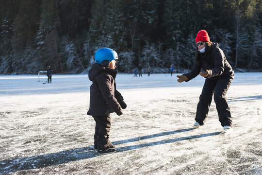 Parent Teaching Child Ice Skating Outdoors
