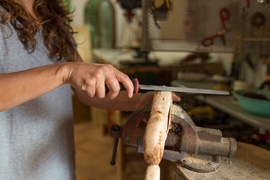 Craftswoman filing a piece of wood in her workshop