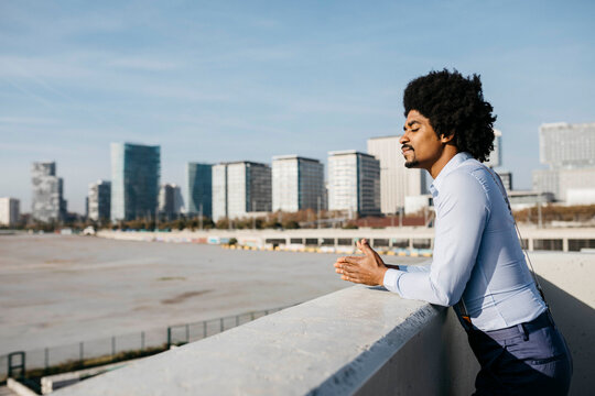 Spain, Barcelona, man leaning on balustrade enjoying sunlight