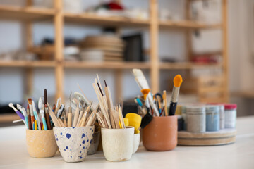 Tools for working with clay close-up. Brushes, stacks and loops for working with ceramics in glasses on the table