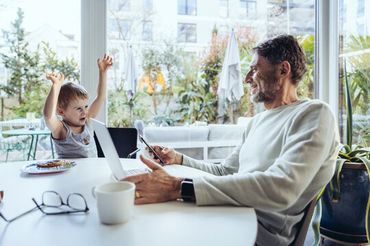 Little boy trying to get attention, while father is working from home