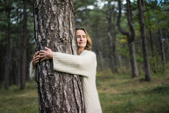 Woman hugging tree in forest