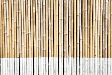 Bamboo wall constructed from vertical bamboo stalks arranged side by side.