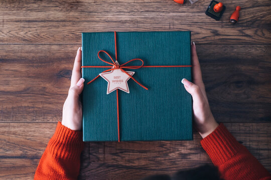 Woman's hands holding Christmas present, from above