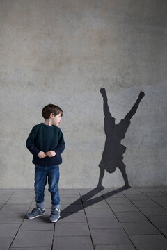 Germany, Duesseldorf, little boy looking at shadow of Duesseldorf's cartwheeler on wall in the background