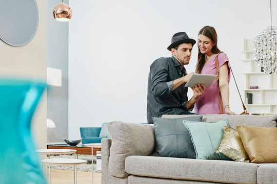 Couple choosing furniture in shop, using digital tablet