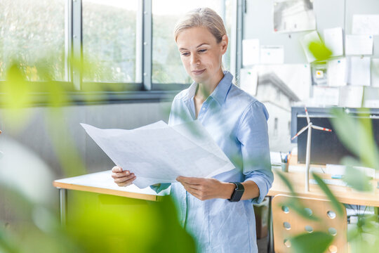 Woman in office working on plan with wind turbine model on table