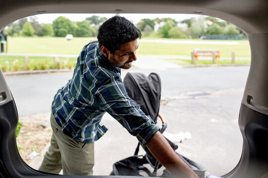 Indian man unloading pram from car boot