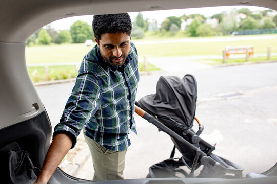 Indian man unloading pram from car boot