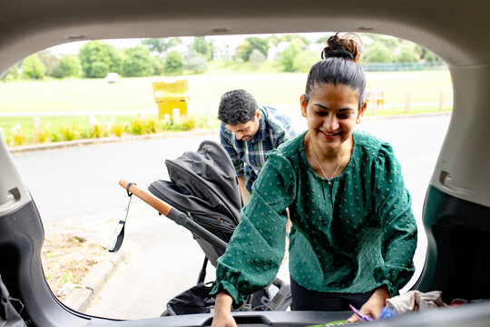 Indian woman unpacking car boot in the parking space