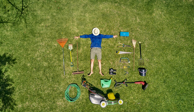 View from above of a gardener with sun hat on his face, laying on the grass with all the tools he need for take care of garden
