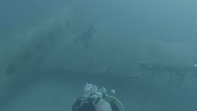 log footage of scuba divers are exploring a c47 dakota airplane wreck underwater 