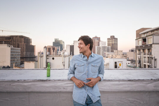 Confident young man standing on a rooftop terrace