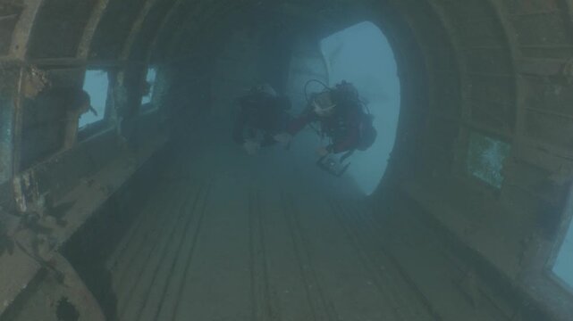 log footage of scubadivers exploring airplane wreck underwater