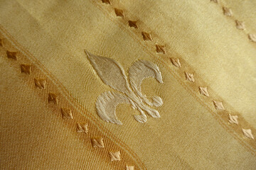 Background - beige fabric with embroidered fleur de lis symbol © Anna