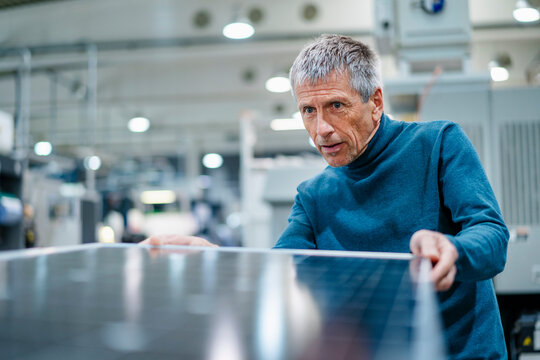 Senior man examining solar panel at industry