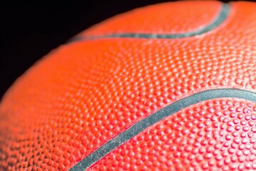 Fototapeta premium Red basketball ball texture macro close up showing dimpled surface for sports equipment advertising and fitness marketing background with copy space on black area