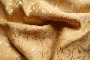 Crumpled gold and white silky brocade fabric with floral pattern