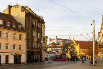 Fototapeta premium Modern tram travels along a quiet Hurbanovo street in Bratislava during a day with historical architecture in view