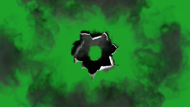Dynamic visual effect of a realistic bullet hole impact with jagged edges and smoky debris, isolated on a vibrant green screen for easy compositing in action sequences and explosive overlays