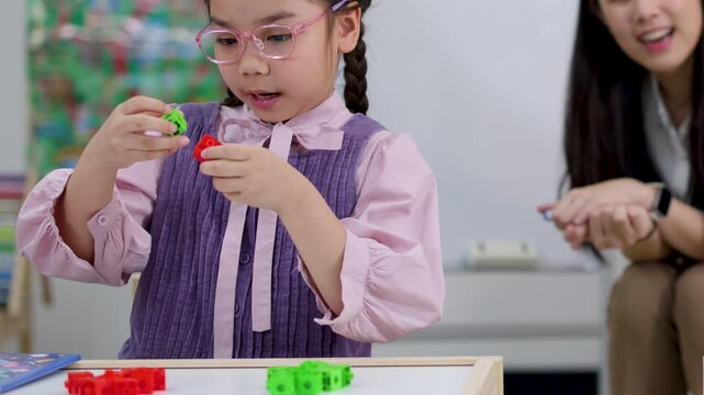 Young Asian Girl Counting Math Blocks in an Elementary Classroom Setting
