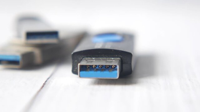 Close-up motion of usb 3.0 flash drive connectors on white wooden table