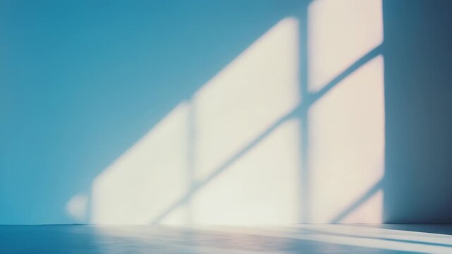 Gentle sunlight filters through large window panes, casting soft geometric shadows on a blue wall and floor, creating a calm and minimalist atmosphere filled with morning tranquility