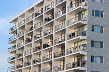 Fototapeta premium Modern apartment building with stacked balconies and glass railings in a coastal urban neighborhood.