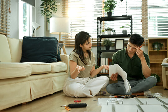 Frustrated asian couple having problems while assembling furniture