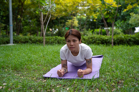 Beautiful young woman practicing Padmasana on yoga mat outdoors, space for text.