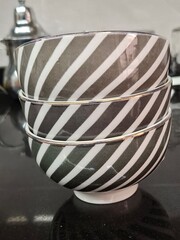Stack of Modern Gray and White Striped Ceramic Bowls on a Black Kitchen Counter