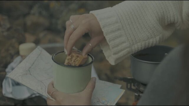 Woman enjoying snack in nature with camping mug