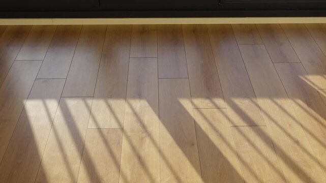Sunlight creates striped shadows on polished wooden floorboards