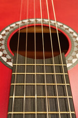 Obraz premium Close-up of a vibrant red acoustic guitar with strings and soundhole detail.