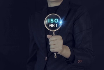 Business professional holding magnifying glass with ISO 9001 text, quality management system certification concept, compliance audit, standard assurance, risk control corporate governance.
