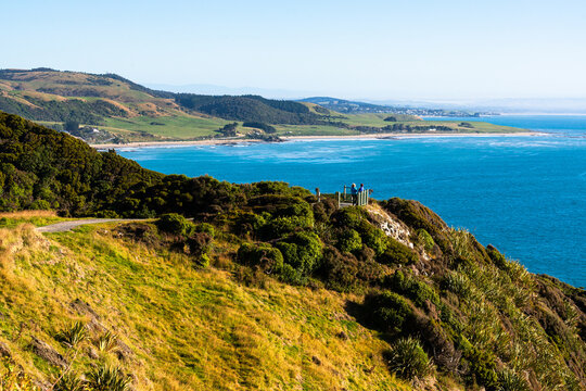 View from headland  to lookout with people and beyond to deep blue sea