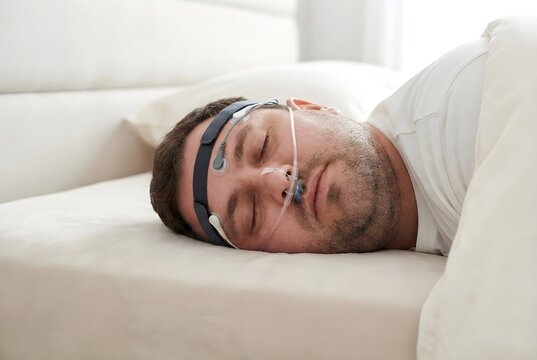 Adult Caucasian Man Undergoing Sleep Study Polysomnography Test with Electrodes and Nasal Cannula for Sleep Apnea Diagnosis at Home