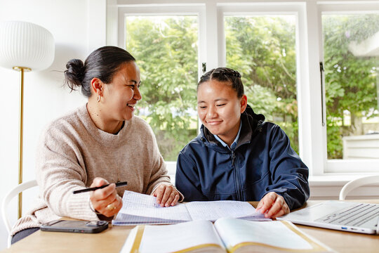 Samoan mum helping teenage daughter with her school workbook