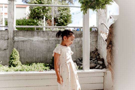 Young Samoan girl standing in the porch with wooden bench