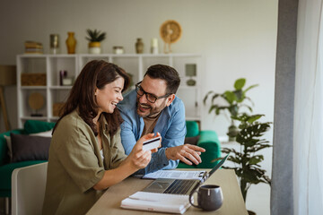 Fototapeta premium Couple shopping online using credit card and laptop at home
