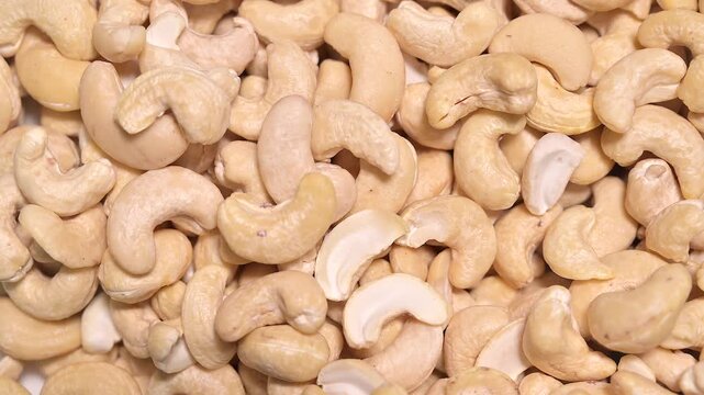 Top view video of raw natural cashew nuts slowly rotating to showcase their texture, shape, and organic freshness. The close perspective emphasizes detail, surface quality, and wholesome food appeal
