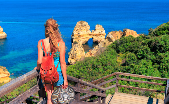 holiday maker with bag and hat looking at famous Algarve beach, rock formation, praia do camilo, Lagos in Portugal