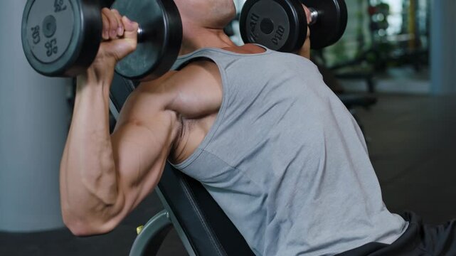 Muscular man performing incline press in a gym, demonstrating strength and fitness for body building program and exercise lifestyle